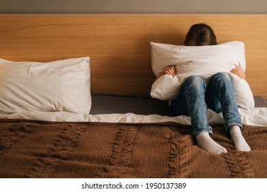 Portrait Of Unrecognizable Upset Little Girl Crying Sitting Alone In Fetal Position Hiding Face And Rocking On Bed Hugging Big Pillow. Concept Of Child Depression.