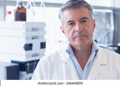 Portrait Of An Unsmiling Scientist Wearing Lab Coat In Laboratory