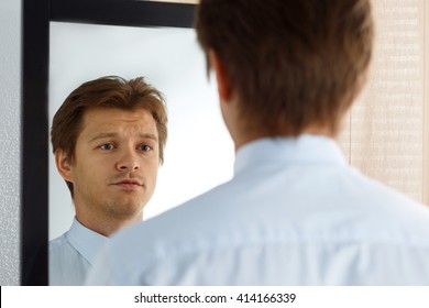 Portrait of unsure young businessman with unhappy face looking at the mirror. Man preparing for important meeting, new job interview or dating. Difficult relationship, stress management concept