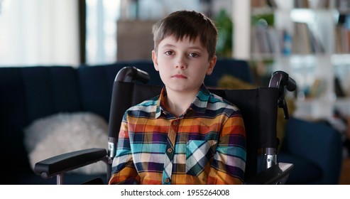 Portrait Of Unwell Caucasian Disabled Child Sitting In Wheelchair Looking At Camera. His Happy Old Er Sister Having Fun Playing With Socilal Media On Smartphone. Diversity.