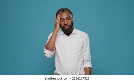 Portrait Of Upset Adult Dealing With Headache And Migraine, Rubbing Temples To Cure Pain And Suffering. Stressed Sick Person Feeling Unwell And Sad About Physical Ache, Waiting To Solve Problem.