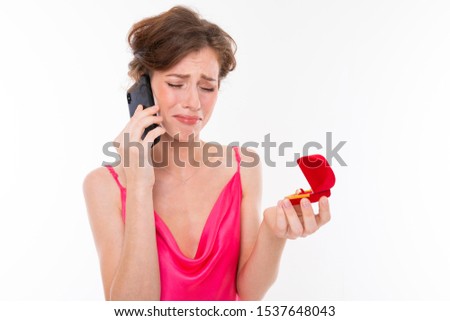 portrait of an upset bride with a wedding ring in her hands, a distressed girl phoning and crying