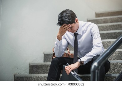 Portrait of an upset businessman at desk in office. Businessman being depressed by working in office.Strain,Yong business man to think and not Work with stress Pretending to put his hand to the head.