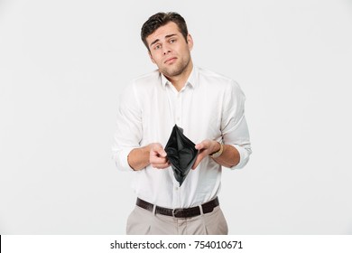 Portrait of an upset frustrated man showing empty wallet and shrugging shoulders isolated over white background