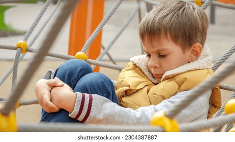 Portrait of upset little boy sitting alone on the playground and feeling sad. - Powered by Shutterstock