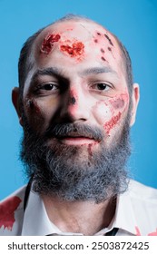 Portrait of upset man full of bloody bruises, victim of domestic violence at home, hurting. Close up shot of injured sad person with wounds and scars on face after beating, studio background