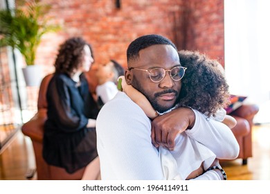 Portrait of upset man hugs his cute curly baby girl in living room