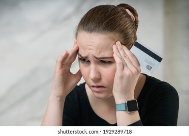 Portrait Of Upset Sad Frustrated Girl, Young Disappointed Woman Holding Credit Bank Card And Her Head With Hand, Crying. Problems With Money, Bank, Job. Unemployment, Poverty. Internet Online Fraud.