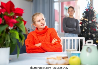 Portrait of upset woman sitting at the table at kitchen after quarrel with her teenager daughter before Xmas - Powered by Shutterstock