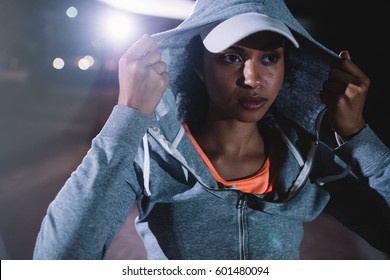 Portrait of urban runner standing on the street at night. Young woman in sportswear standing outdoors. - Powered by Shutterstock