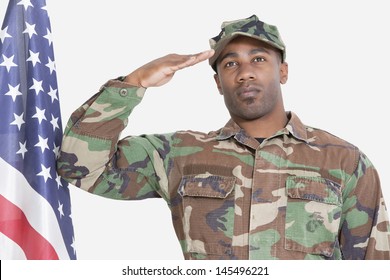 Portrait Of US Marine Corps Soldier Saluting American Flag Over Gray Background