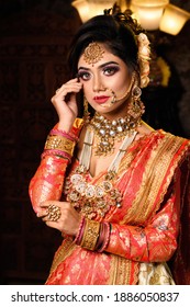 Portrait of very beautiful young Indian bride in luxurious bridal costume with makeup and heavy jewellery in studio lighting indoor. Wedding fashion.