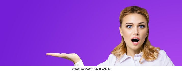 Portrait of very happy, excited surprised, astonished businesswoman with wide opened eyes, mouth, showing copy space text area. Success in business concept. Violet purple background. Astonishment