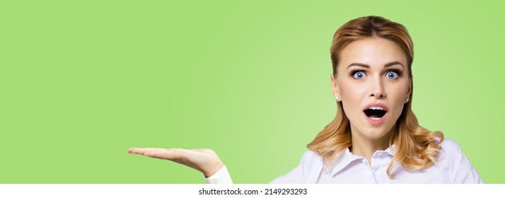Portrait of very happy, excited surprised, astonished businesswoman with wide opened eyes, mouth, showing ad copy space text area. Success in business concept. Green colour background. Astonishment.