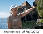 Portrait of a very happy senior women sitting outdoors on a sunny day at Lake Geneva while takes a selfie, Tourism, travel, relax and retirement