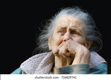 Portrait of a very old and tired of life wrinkled woman outdoors with a hand near her face