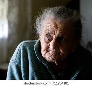 Portrait Of A Very Old Tired Woman Sitting Near A Window