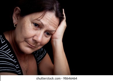 Portrait Of A Very Sad And Depressed Older Woman Suffering From Stress Or A Strong Headache Isolated On Black