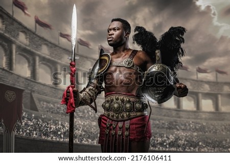 Portrait of victorious gladiator of african ethnic holding plumed helmet and spear in coliseum.
