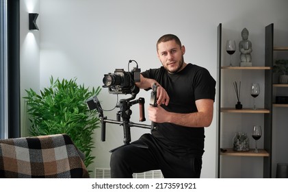 Portrait of videographer man posing indoors with camera mounted on gimbal stabilizer equipment. - Shutterstock ID 2173591921