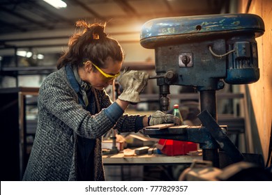 Portrait view of focused serious middle aged professional female carpentry working with an electric drill in the workshop. - Powered by Shutterstock