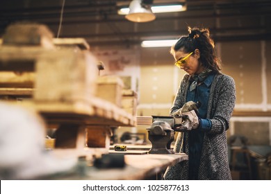 Portrait View Of Satisfied Smiling Middle Aged Professional Female Carpentry Worker With Steel Vise On The Table In The Workshop.