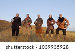 Portrait of Vikings standing with swords and helmets in hands. Dressed in chain mail. Medieval Reenactment.