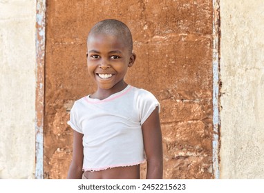 portrait of a village african child, in front of the wall of the house