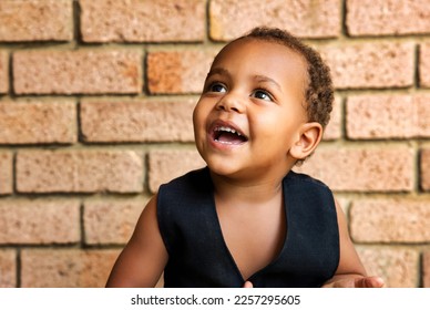 portrait of a village happy african boy laughing next to a brick wall in the yard in the late afternoon