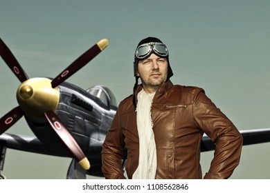 Portrait Of A Vintage Pilot With Leather Cap, Scarf And Aviator Glasses In Front Of A Historic Airplane - Portrait Of A Man In Historical Pilot Clothing