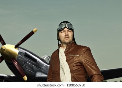 Portrait Of A Vintage Pilot With Leather Cap, Scarf And Aviator Glasses In Front Of A Historic Airplane - Portrait Of A Man In Historical Pilot Clothing