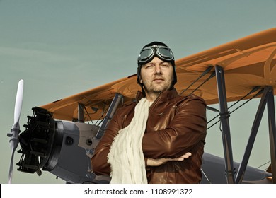 Portrait Of A Vintage Pilot With Leather Cap, Scarf And Aviator Glasses In Front Of A Historic Airplane Biplane - Portrait Of A Man In Historical Pilot Clothing