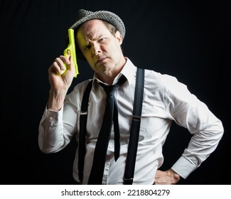 Portrait Of Vintage Private Eye Detective In Suspenders And Fedora Holding Toy Gun. Comedic  Action Hero.