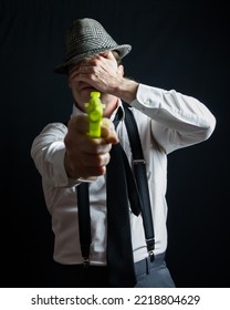 Portrait Of Vintage Private Eye Detective Aiming Toy Gun While Covering His Eyes. Comedic Action Hero Concept.