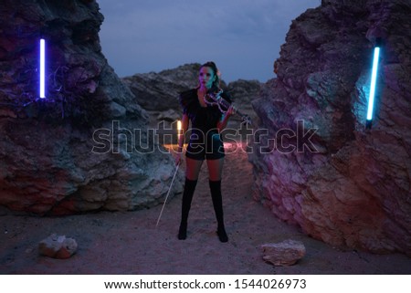portrait of violinist girl in black dress with her violin with colorful lights in the beach at night
