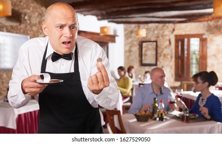 Portrait Of Waiter In Black Apron Upset With Little Tips At Restaurant