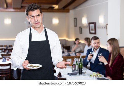 Portrait Of Waiter Dissatisfied With Small Tip From Restaurant Visitors .