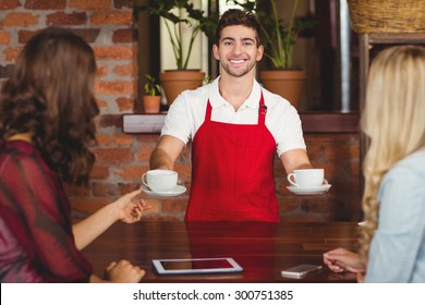 Portrait of a waiter serving coffees to customers at the coffee shop - Powered by Shutterstock