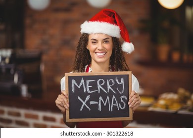 Portrait of a waitress with a chalkboard merry x-mas at the coffee shop - Powered by Shutterstock