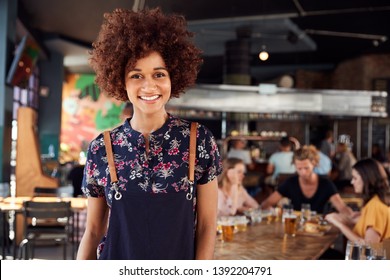 Portrait Of Waitress Serving In Busy Bar Restaurant