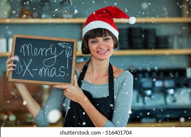 Portrait of waitress showing slate with merry x-mas text against snow falling - Powered by Shutterstock