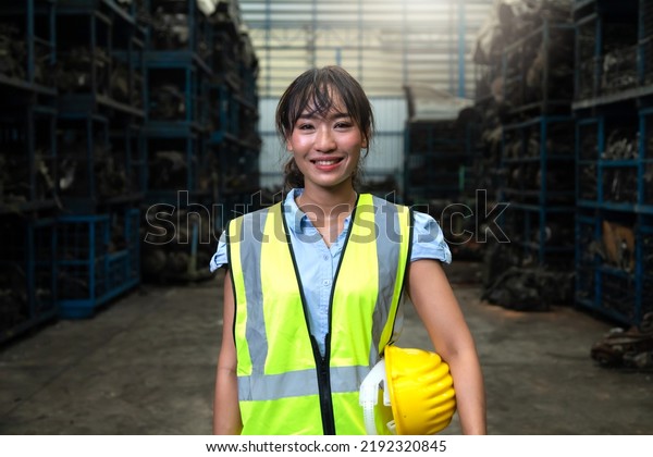 Portrait
warehouse managers or worker asian woman working  at large
distribution warehouse of old car
part.