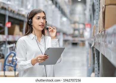 Portrait of warehouse woman staff using digital tablet and talking to customer with headset working in distribution factory. female call center or support operator working for online shopping.