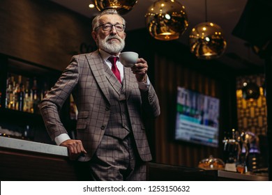 Portrait of wealthy prosperious senior businessman in drinking coffee near bar counter at elite gentlemen club