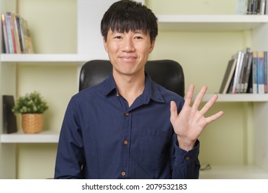 Portrait webcam of happy young adult Asian businessman is smiling, waving hands when talk on webcam, video call to coach or teach online business class as trading, investment on money, Cryptocurrency.