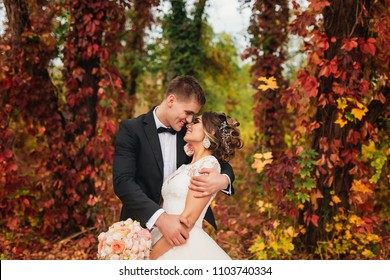 Portrait Of A Wedding Couple In Autumn Nature. They Hug And Pose