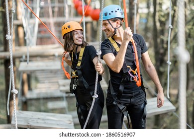 Portrait of a well-equipped man and woman having an active recreation, climbing ropes in the park with obstacles outdoors - Powered by Shutterstock