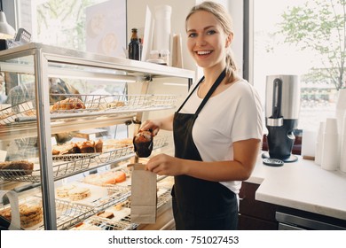 Portrait of white Caucasian beautiful barista woman taking muffin pastry from shop-window. Person at work place, small business concept - Powered by Shutterstock