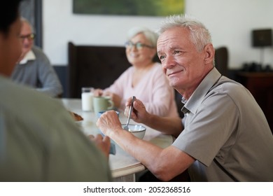 Portrait of white haired senior man enjoying breakfast in dining room at nursing home, copy space