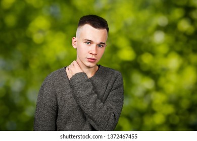 Portrait White Yong Guy In Gray Sweater And Short Haircut, On Green Bokeh Background